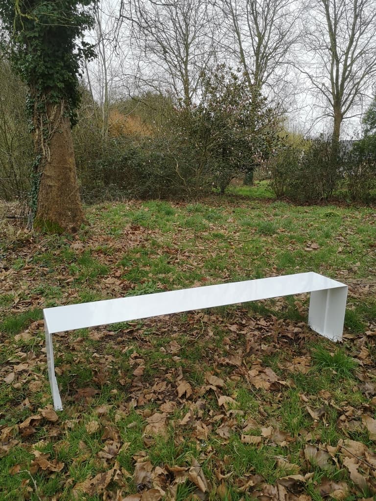 Banc d'extérieur minimaliste blanc en métal thermolaqué aux lignes épurées installé au cœur d'un parc arboré."ULTIMO"