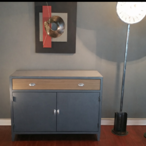 Buffet industriel gris en acier poli avec un tiroir façade chêne et deux portes, dans un salon moderne de style loft.