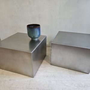 Deux tables basses cubiques en inox brossé sur mesure avec un vase bleu posé sur l'une d'elles.
