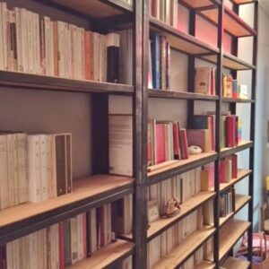 Bibliothèque sur mesure style industriel en acier noir et étagères en bois d'épicéa massif, remplie de livres.